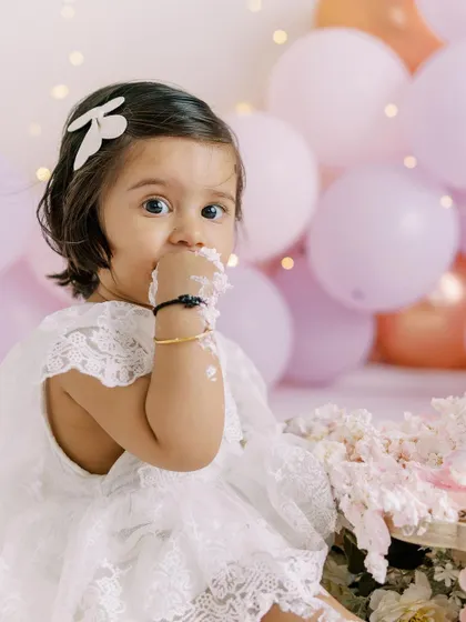 A baby girl's curious look during her cake smash. Her expression is priceless as she decides what to do with the cake.