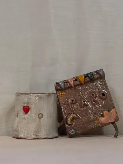 A student's love story in clay. This set, featuring a heart-stamped mug and a storybook-inspired wall hanging, shows the beautiful narrative that can be created in a single workshop session.