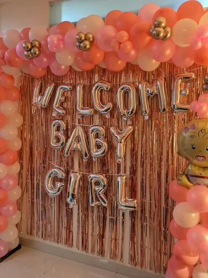 A close-up of the 'Welcome Baby Girl' backdrop, highlighting the mix of pink, white, and metallic balloons, along with a cute baby girl foil balloon.