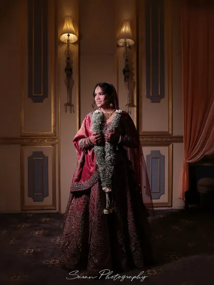 A full-length bridal portrait in a dimly lit, classic room, creating a moody and sophisticated atmosphere.