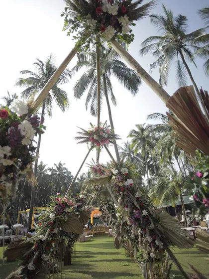 A unique triangular entrance arch designed for a tropical-themed carnival. The structure, made of bamboo and adorned with dried palms and fresh flowers, created a striking and natural gateway to the event.