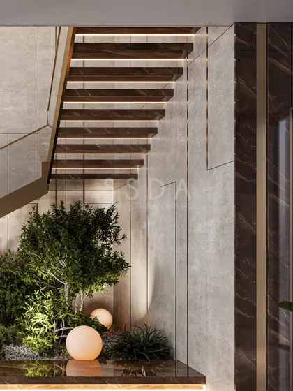 A close-up of the indoor garden beneath the staircase. The combination of natural plants, soft lighting, and rich materials like wood and marble creates a serene and layered experience.