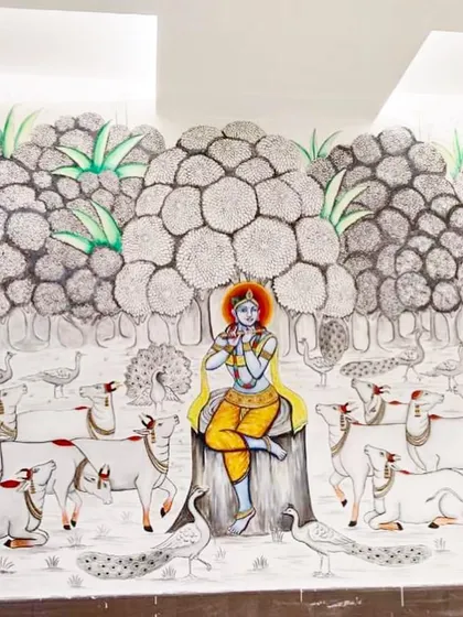 The finished Pichwai mural of Krishna in Mathura. The wall is filled with intricately detailed trees, peacocks, and a herd of devoted cows, creating a grand and spiritual masterpiece.