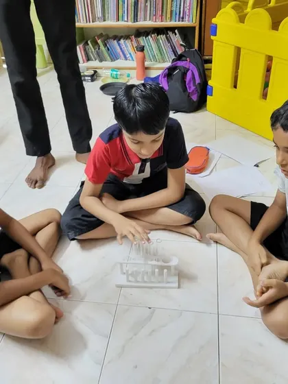 Students discuss their observations while gathered around a set of test tubes on the floor.