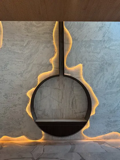 A detailed shot of the installed fireplace, showcasing the precision of the backlighting that traces the organic cutout in the marble wall. This highlights the technical execution required to achieve the seamless final look.