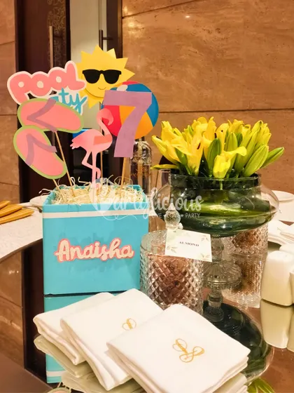 The details make the party. A custom centerpiece for a pool party, featuring fun cutouts like a sun with sunglasses, flip-flops, and a flamingo.