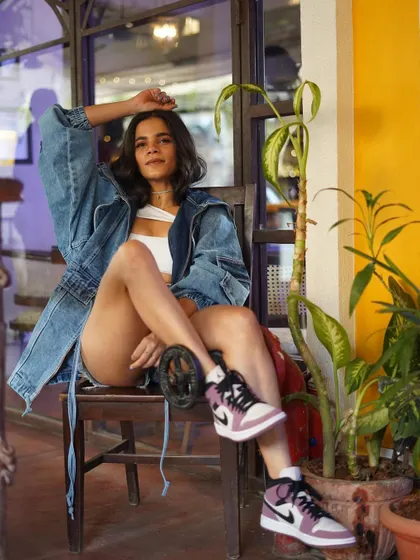 A relaxed, seated pose that still shows off the cool, edgy vibe of the outfit. The sneakers are the perfect finishing touch.