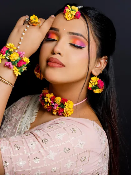 A vibrant and colorful Mehendi bridal makeup look by a student. The eye makeup shows a beautiful blend of sunset colors, perfect for the occasion.