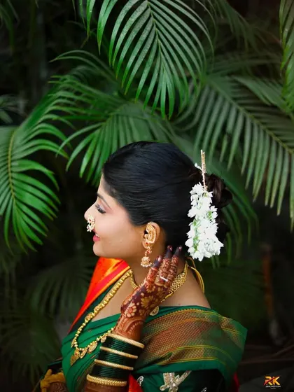 A side profile of the bride, showcasing her elegant hair bun adorned with fresh white gajra. This shot highlights the classic beauty of a traditional bridal hairstyle.