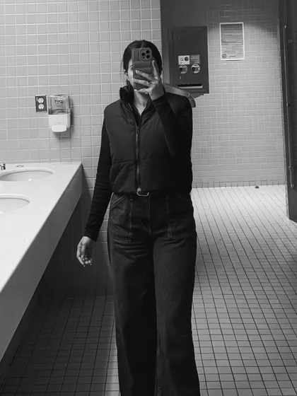 A black and white mirror selfie, adding an artistic touch to this casual college outfit featuring a vest and wide-leg pants.
