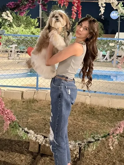 A guest holds her fluffy Shih Tzu high, posing inside our heart-shaped floral wreath. A perfect picture of pet love.