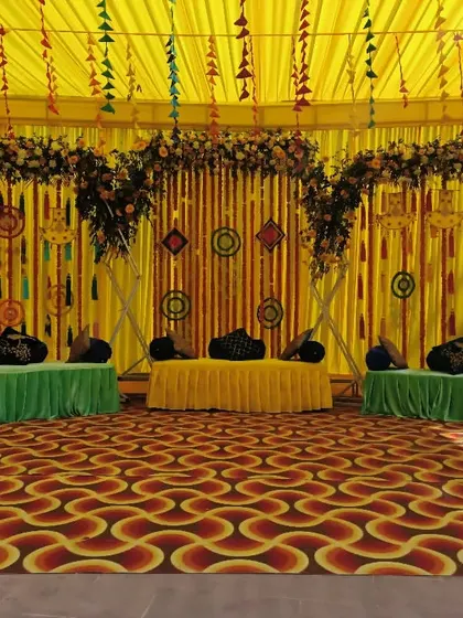 A vibrant Mehendi stage with colorful backdrops, floral arches, and comfortable low seating for the couple and guests.