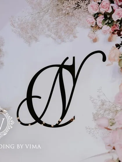 A classic and elegant reception setup symbolizing everlasting love. The stage features a modern, minimalist backdrop with custom monograms, floral arrangements, and soft lighting.