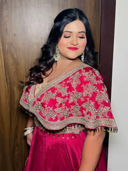A vibrant party look with a bold red lip and soft glam eyes. The client is wearing a beautiful magenta and gold outfit.