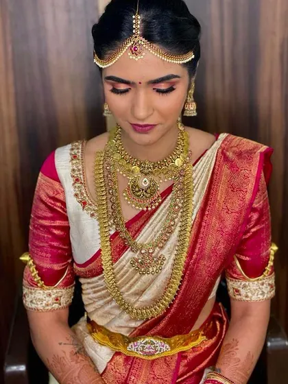 The complete look for this bride, featuring a neat hair bun, traditional jewelry, and flawless makeup that will last throughout the long ceremony.