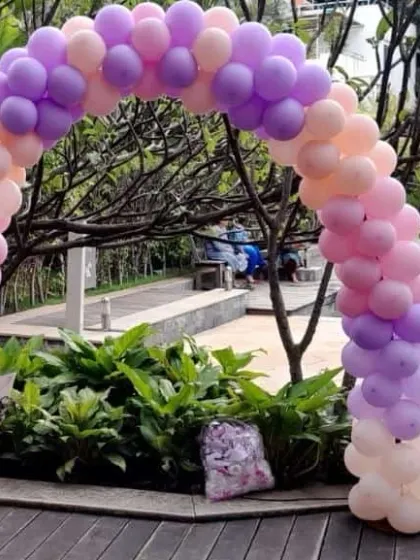 A pastel-colored balloon arch set up by a poolside for a butterfly-themed birthday party.