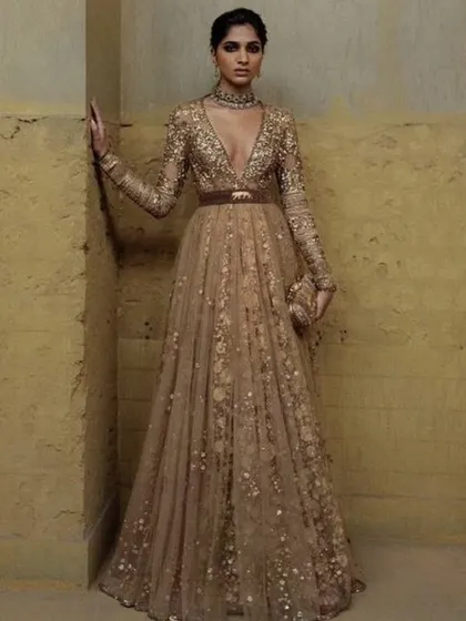 A beautiful belted gown in a muted gold tone. The V-neck and full sleeves, combined with the all-over embellishment, create a look of sophisticated glamour.