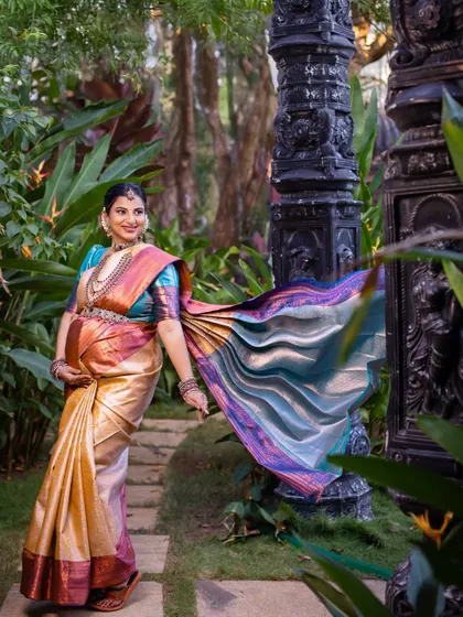 The flowing saree in this walking shot creates a beautiful sense of movement and grace in the garden setting.