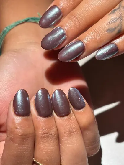 This chic and modern manicure features a pearlescent, metallic brown polish on oval-shaped nails. The subtle shimmer gives it a sophisticated and high-fashion finish.
