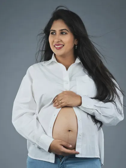 Capturing the radiant glow of pregnancy. This image showcases a candid, happy moment during a maternity session, with natural light and a simple setting to keep the portrait feeling fresh and timeless.