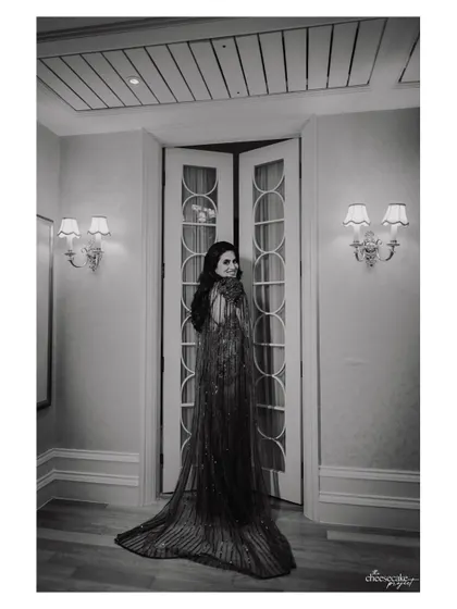 A full-length black and white portrait of the bride, showcasing the stunning detail and train of her gown.