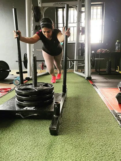 A client pushes a heavily loaded sled, a true test of strength and conditioning.