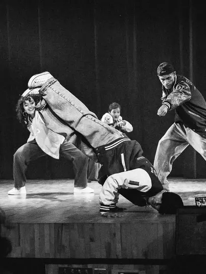 A dynamic shot capturing a b-boy mid-freeze during a high-energy routine. This black and white photo highlights the power and artistry of street dance on stage.