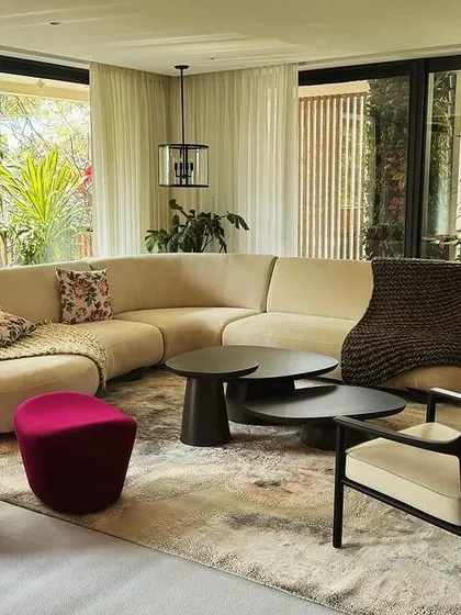 We designed this living space around a custom curved sofa that encourages conversation, complemented by a sculptural magenta lounge chair. The furniture works together to create a room that is open, connected to the outdoors, and full of personality.