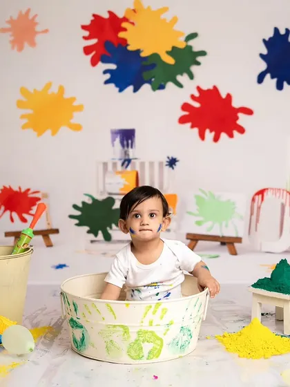A shot from the Holi mini session, with the baby sitting in a tub surrounded by colorful powder and props.