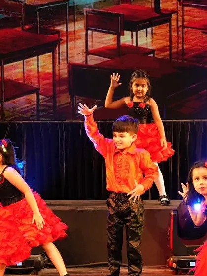 Our little performers using the stage levels to create a dynamic and visually interesting classroom-themed performance.
