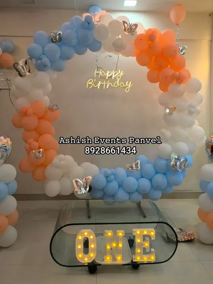 Ring balloon arches are a modern and elegant choice for first birthdays. For this setup, I used a soft pastel color palette of blue, orange, and white, and added a lit-up 'ONE' sign to complete the look.