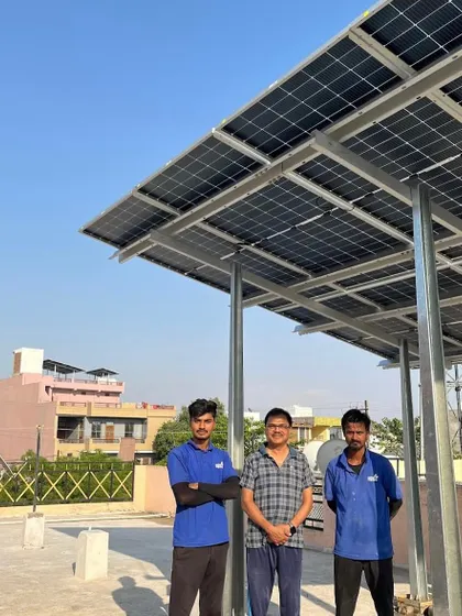 A customer stands with our team members under his new elevated solar panel structure.
