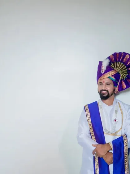 A minimalist portrait of the groom against a white background, making his vibrant purple turban stand out.
