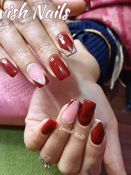 A modern design featuring deep red polish paired with accent nails that have a geometric pink section outlined in silver glitter.