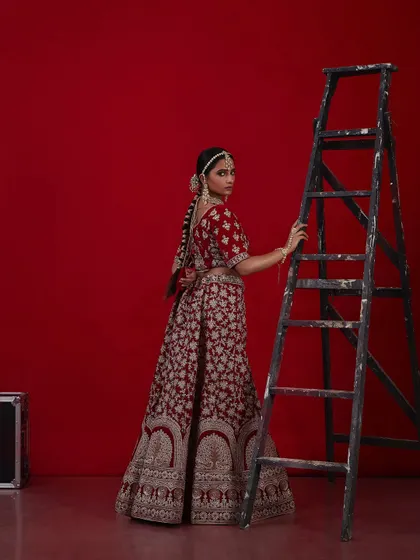 Another angle of the regal red bridal look, showing the intricate details of the outfit and the classic hair and makeup.