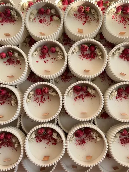A top-down view of the white concrete jars, filled with wax and decorated with dried rosebuds and baby's breath.