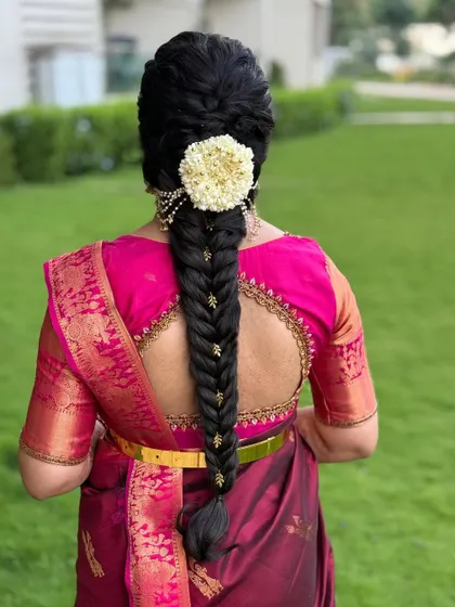 A closer look at the elegant fishtail braid with delicate gold accessories woven in. The simplicity of this style, paired with a traditional jasmine veni, creates a look of pure sophistication.
