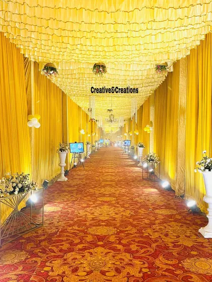 A still shot of the grand yellow entrance tunnel. The warm lighting and repeating floral stands create a sense of scale and grandeur.