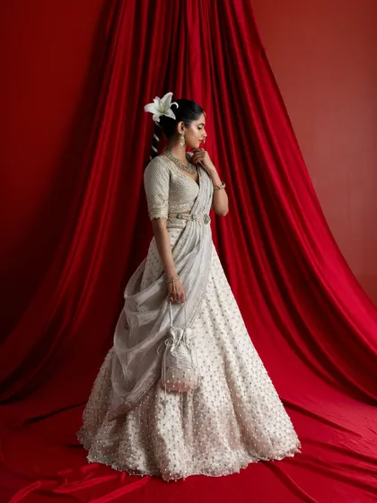 The bride, adorned with a flower in her hair, holds a matching embroidered potli bag. This image showcases the complete, coordinated look I create, ensuring every accessory complements the main garment perfectly.
