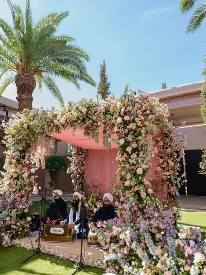 The Anand Karaj setup in Marrakech, with soulful Gurbani singers performing under a lush floral arch, creating a deeply spiritual atmosphere.