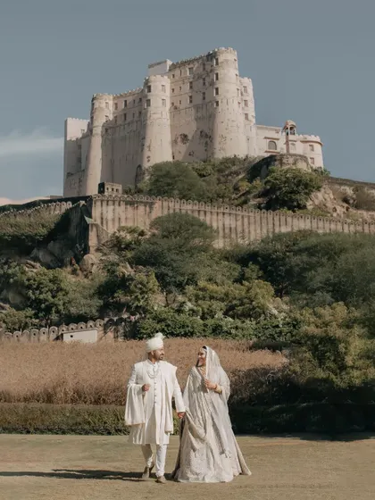 A breathtaking portrait of the couple with the Alila Fort Bishangarh in the background. This shot perfectly encapsulates the concept of a royal destination wedding in Rajasthan.