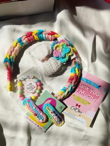 This colorful gift hamper for Rida includes a rainbow braided headband, a custom name bracelet, and personalized hair clips.