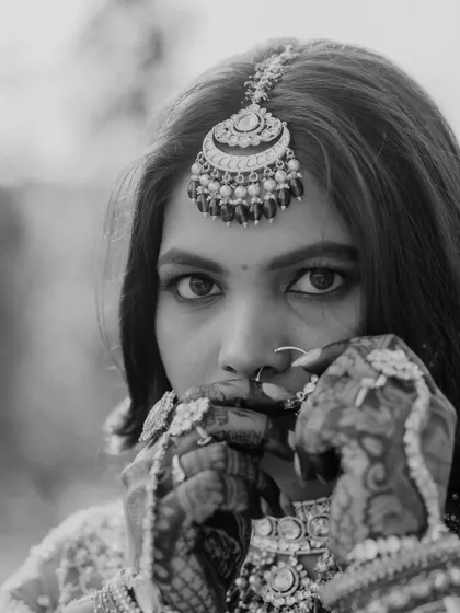 A striking black and white portrait that emphasizes the eyes and the intricate details of her henna. This artistic shot shows the timeless quality of the makeup.