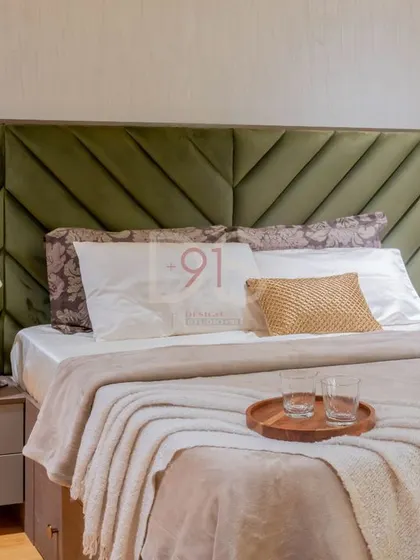 A close-up of a master bedroom with an olive green upholstered headboard, showcasing a cozy and elegant design.