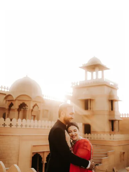 An intimate embrace against a grand, sunlit palace. This photo captures a tender moment, combining the epic scale of the location with the personal connection of the couple.