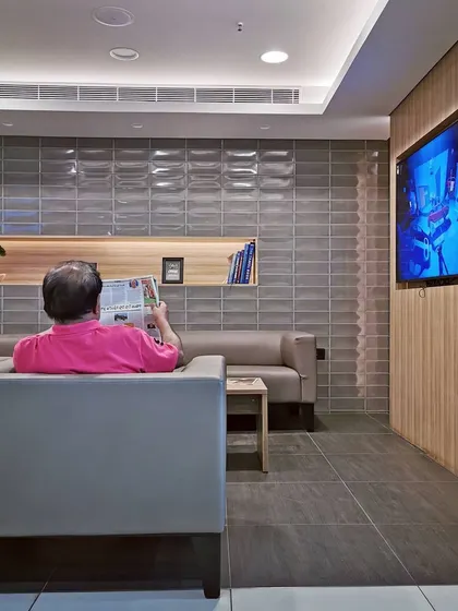 A closer look at the customer waiting lounge, highlighting the use of textured grey tiles and warm wood accents. These material choices create a calm and sophisticated atmosphere, distinct from the main showroom floor.