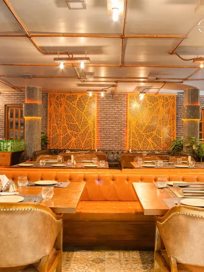 For Charcoal Restaurant in Bangalore, I designed an interior with a rustic and industrial feel. The space features exposed brick walls, visible copper piping for lighting, and comfortable tan leather seating to create a warm, inviting atmosphere.