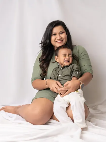 A mother holds her laughing son. His unrestrained joy is contagious, making this a wonderfully happy and candid portrait.