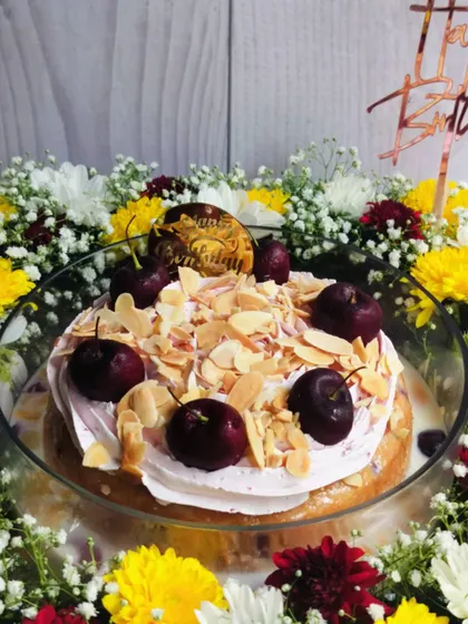 A closer look at the Cherry Almond Tres Leches cake, showing the creamy texture of the whipped cream, fresh cherries, and the generous sprinkle of toasted almonds.