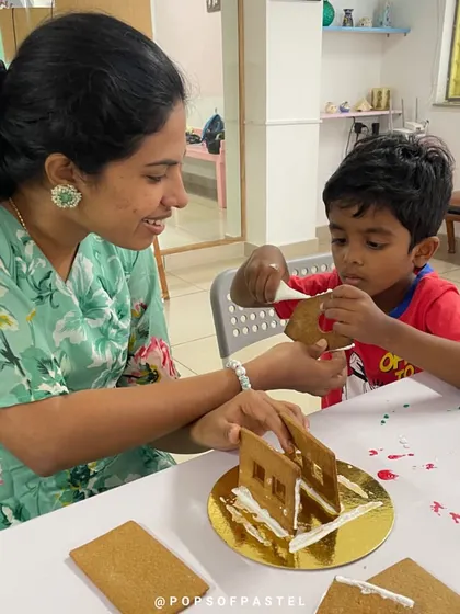 A mother helps her son assemble the walls of his gingerbread house, the first step in this fun, edible construction project.